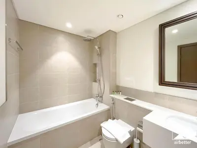 a bathroom with a tub and a toilet and a sink at Seaside 1BR Retreat , Beach & Atlantis Views in Dubai