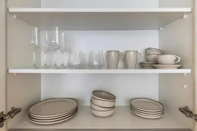 a shelf with plates and glasses and dishes on it at District One Dubai Lagoon View Near Downtown in Dubai