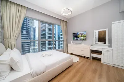 a bedroom with a white bed and a desk and a window at Upgraded Bay Central 1 Bed - Marina and Pool View in Dubai