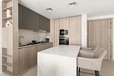 a kitchen with a white counter top and wooden cabinets at VayK - Stylish 2BR with Premium Amenities in JVC in Dubai