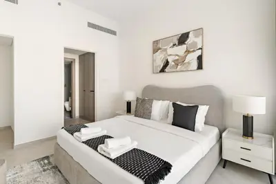 a white bedroom with a large bed in a room at VayK - Stylish 2BR with Premium Amenities in JVC in Dubai
