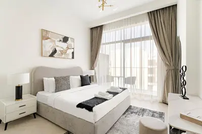 a white bedroom with a large bed and a window at VayK - Stylish 2BR with Premium Amenities in JVC in Dubai