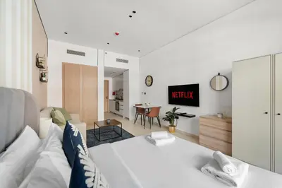 a living room with a white couch and a tv at VayK - Contemporary and Cozy Studio in JVC in Dubai