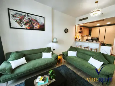 a living room with two green couches and a kitchen at Luxury 1BHK Pool Paddle Sauna in Dubai