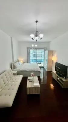 a bedroom with a bed and a couch and a tv at Zing Holiday Home in Dubai