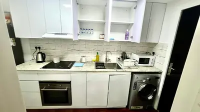 a kitchen with white cabinets and a sink and a washer at Zing Holiday Home in Dubai
