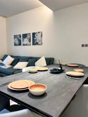 a table with plates and bowls on it in a living room at Sobha Hartland Greens 2BR near Dubai Mall in Dubai