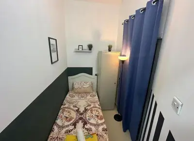 a small room with a bed and blue curtains at Solo Comfort Corner In Barsha 1 in Dubai