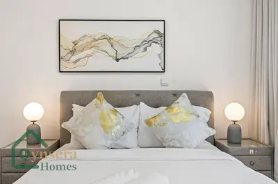 a bedroom with a bed with white pillows and a painting at Iconic Burj & Fountain View Retreat! in Dubai