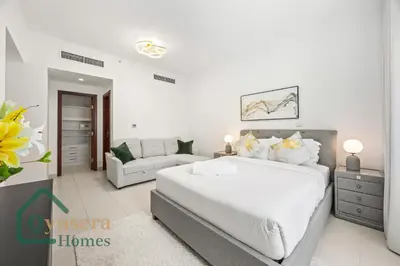 a white bedroom with a large bed and a couch at Iconic Burj & Fountain View Retreat! in Dubai