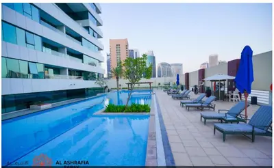 a swimming pool with chairs and umbrellas next to a building at Dreamstay 2 BR in Business Bay in Dubai