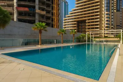 a large swimming pool with palm trees and buildings at Gala Guests - Iris Blue Luxe Living Collection in Dubai