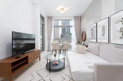 a living room with a white couch and a tv at Gala Guests - Iris Blue Luxe Living Collection in Dubai