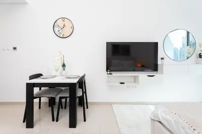 a dining room with a table and a tv on a wall at Tranquil Studio at Botanica in Dubai