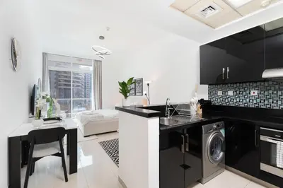 a kitchen with black and white appliances and a table at Tranquil Studio at Botanica in Dubai