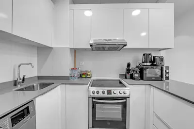a white kitchen with a stove and a sink at Waves - Vibrant and Cozy 1BR Apt in JVC in Dubai