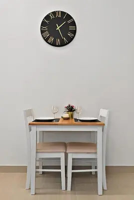 a table and chairs with a clock on a wall at Dusk by Binghatti by Rentujemy in Dubai