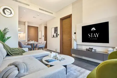 a living room with a tv on a wall at STAY BY LATINEM Luxury 1BR Holiday Home CB 1414 Near Downtown in Dubai
