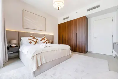 a bedroom with a large white bed and a wooden door at FAM Living -Madinat Jumeirah Living Apartment with Iconic Views in Dubai