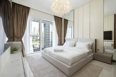 a bedroom with a large white bed and a chandelier at KeyRock - Palm View Apt with Pool & Gym Access in Dubai