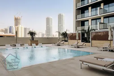 a swimming pool with lounge chairs and a building at Brand New 1BR Fully Furnished in Dubai