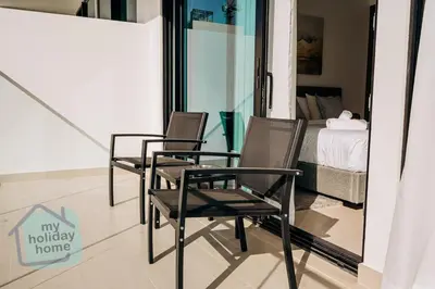 two chairs sitting in a room with a bed at Brand New 1BR Fully Furnished in Dubai