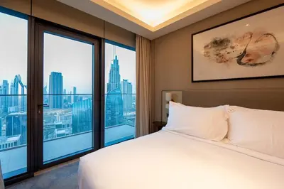 a bedroom with a white bed and large windows at Venetian - Sky 3BR - Address Opera with Burj & Fountain views in Dubai