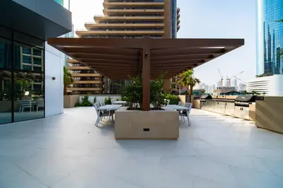 a patio with a table and chairs under a wooden umbrella at SettlerHomes - Liv Marina Luxe With Gym, Pool, Sauna in Dubai