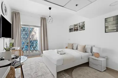 a white bedroom with a white bed and a table at Beautiful Studio Prime location Pool & Gym in Dubai