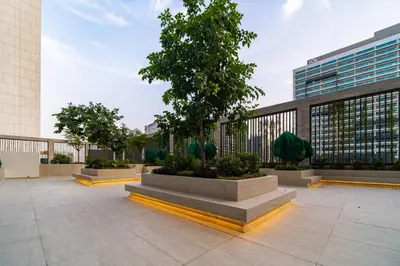 a courtyard with a tree and a building at SettlerHomes - Lux 20F Stay With Gym, Pool & Cinema in Dubai