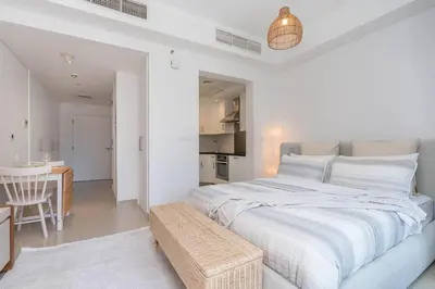 a white bedroom with a large bed and a table at RBA Holidays - Luxury Studio near Burj Khalifa - Downtown Dubai in Dubai