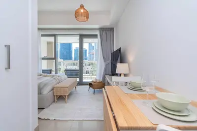 a white living room with a bed and a table at RBA Holidays - Luxury Studio near Burj Khalifa - Downtown Dubai in Dubai