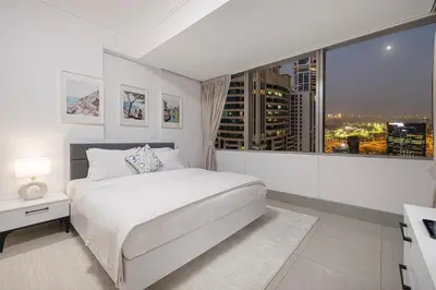 a bedroom with a white bed and a large window at Sea & City View Apartment Dubai Marina - Ravello Living in Dubai