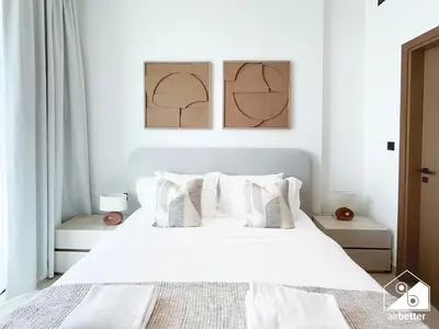 a white bedroom with a white bed with white pillows at Modern 1BR in JVC l Pool, Gym, Parking in Dubai