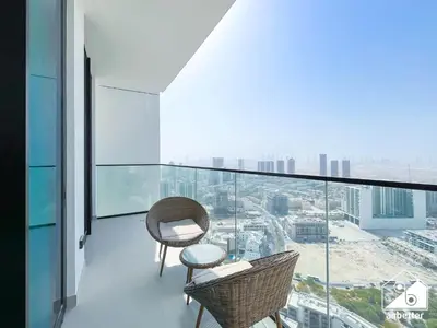 a balcony with two chairs and a view of a city at Modern 1BR in JVC l Pool, Gym, Parking in Dubai