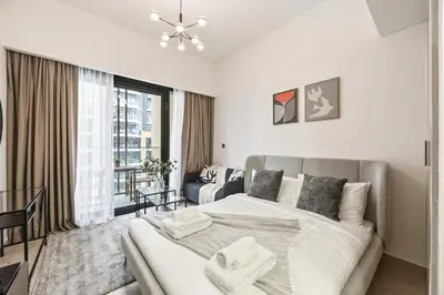 a white bedroom with a bed and a living room at Elite Escape - Getaway in Azizi Riviera 26 in Dubai
