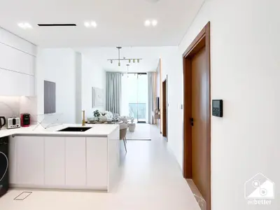 a kitchen with white cabinets and a living room at Dubai JVC 1BR l Stylish Stay with Top Amenities in Dubai