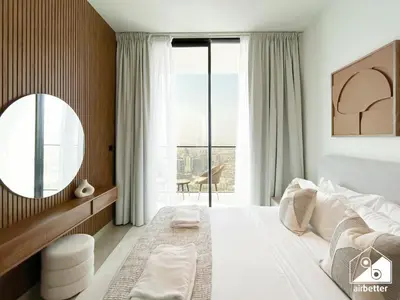a bedroom with a large bed with a mirror and a window at Dubai JVC 1BR l Stylish Stay with Top Amenities in Dubai