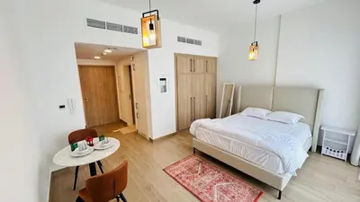 a bedroom with a bed and a table and chairs at studio in best community-podium level with terrace in Dubai