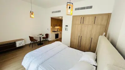 a bedroom with a white bed and a kitchen at studio in best community-podium level with terrace in Dubai