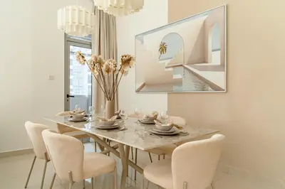 a dining room with a table with chairs and a vase with flowers at The Smart Concierge - Marina Wharf in Dubai