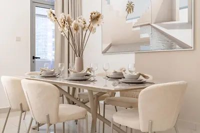 a dining room table with chairs and a vase with flowers at The Smart Concierge - Marina Wharf in Dubai