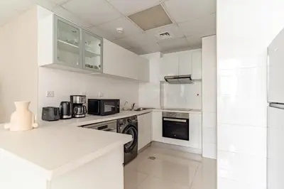 a white kitchen with white cabinets and appliances at The Smart Concierge - Marina Wharf in Dubai