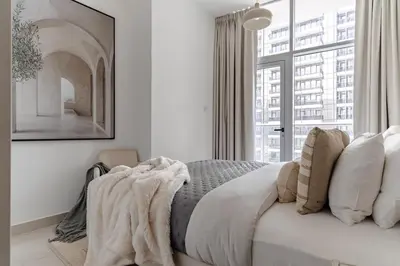 a white bedroom with a bed with pillows and a window at The Smart Concierge - Marina Wharf in Dubai