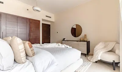 a bedroom with a large white bed and a chair at The Smart Concierge - Burj Views in Dubai