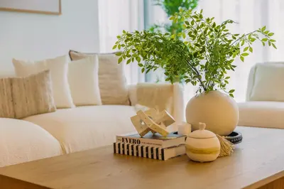 a coffee table with books and a vase on it at Sarora One - Japandi-Inspired 2-Bedroom Apartment in Act One, Downtown Dubai with Balcony & Burj Khalifa View in Dubai