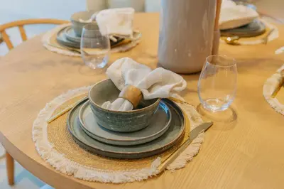 a wooden table with a bowl and plates on it at Sarora One - Japandi-Inspired 2-Bedroom Apartment in Act One, Downtown Dubai with Balcony & Burj Khalifa View in Dubai