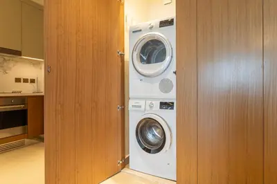 a washer and dryer in a small kitchen at Shukr شكر - Luxury 3BR with Panoramic Burj Khalifa & Fountain Views - Address Residence Dubai Opera - 2 Min Walk to Dubai Mall in Dubai
