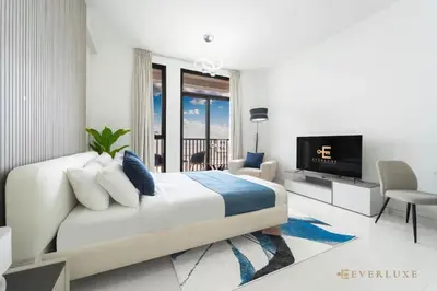 a white bedroom with a large bed and a tv at Cozy Studio With Style Midtown Retreat - Impz in Dubai