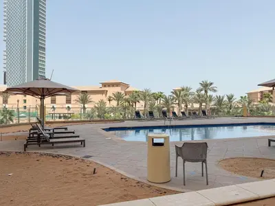a swimming pool with two chairs and a trash can at The Smart Concierge - Murjan in Dubai